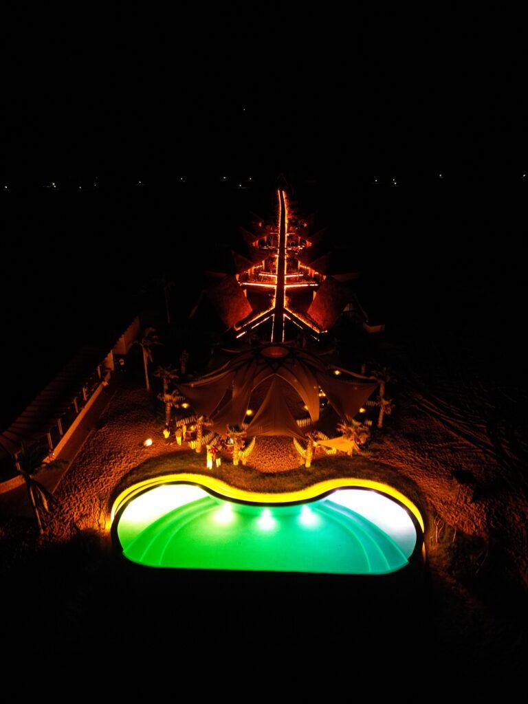 Vista nocturna de la alberca y la palapa central del Parque Astrológico Mayto iluminadas